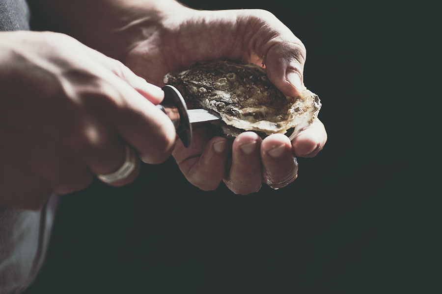 A Man With A Knife Opens A Fresh Oyster